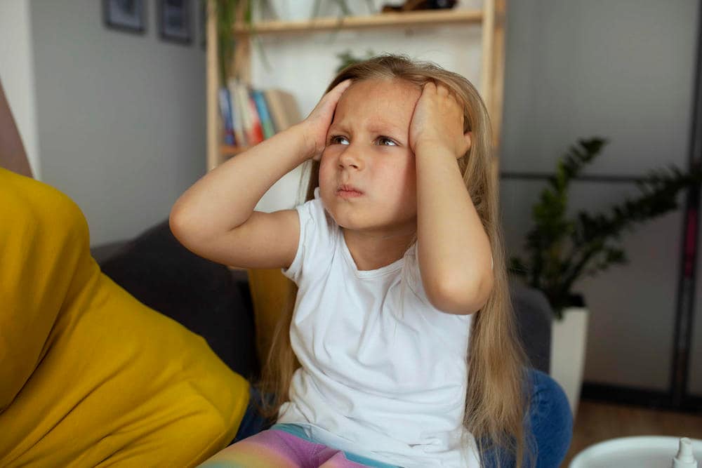HIJA O HIJO TOCANDOSE LA CABEZA REPRESENTANDO MOLESTIAZ EN LA CABEZA. ACTRON PEDIATRICO DOLOR DE CABEZ EN NIÑOS